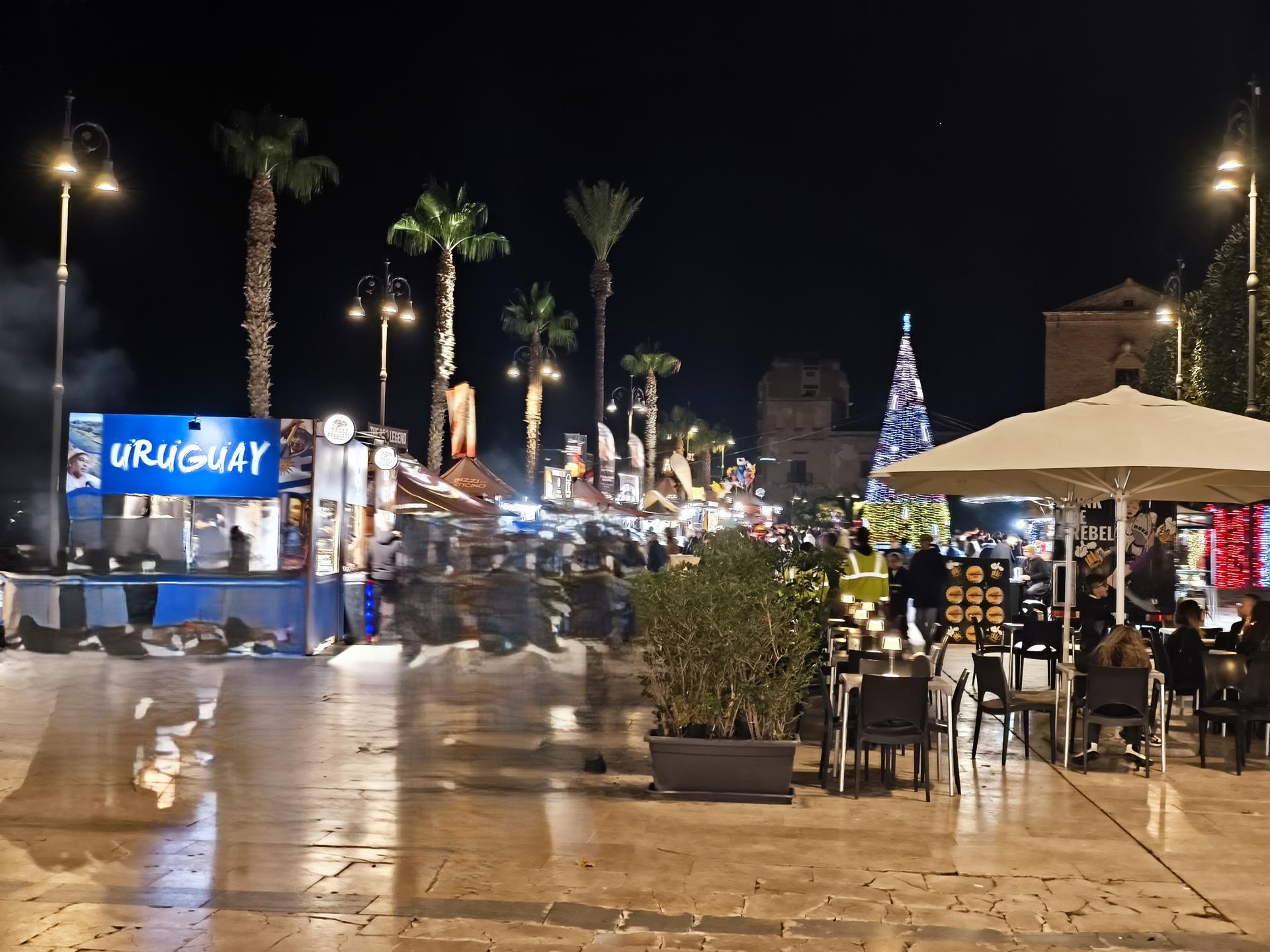 Stand gastronomici dell’International Street Food a Sciacca con cucine internazionali, luci serali e visitatori durante l’evento.